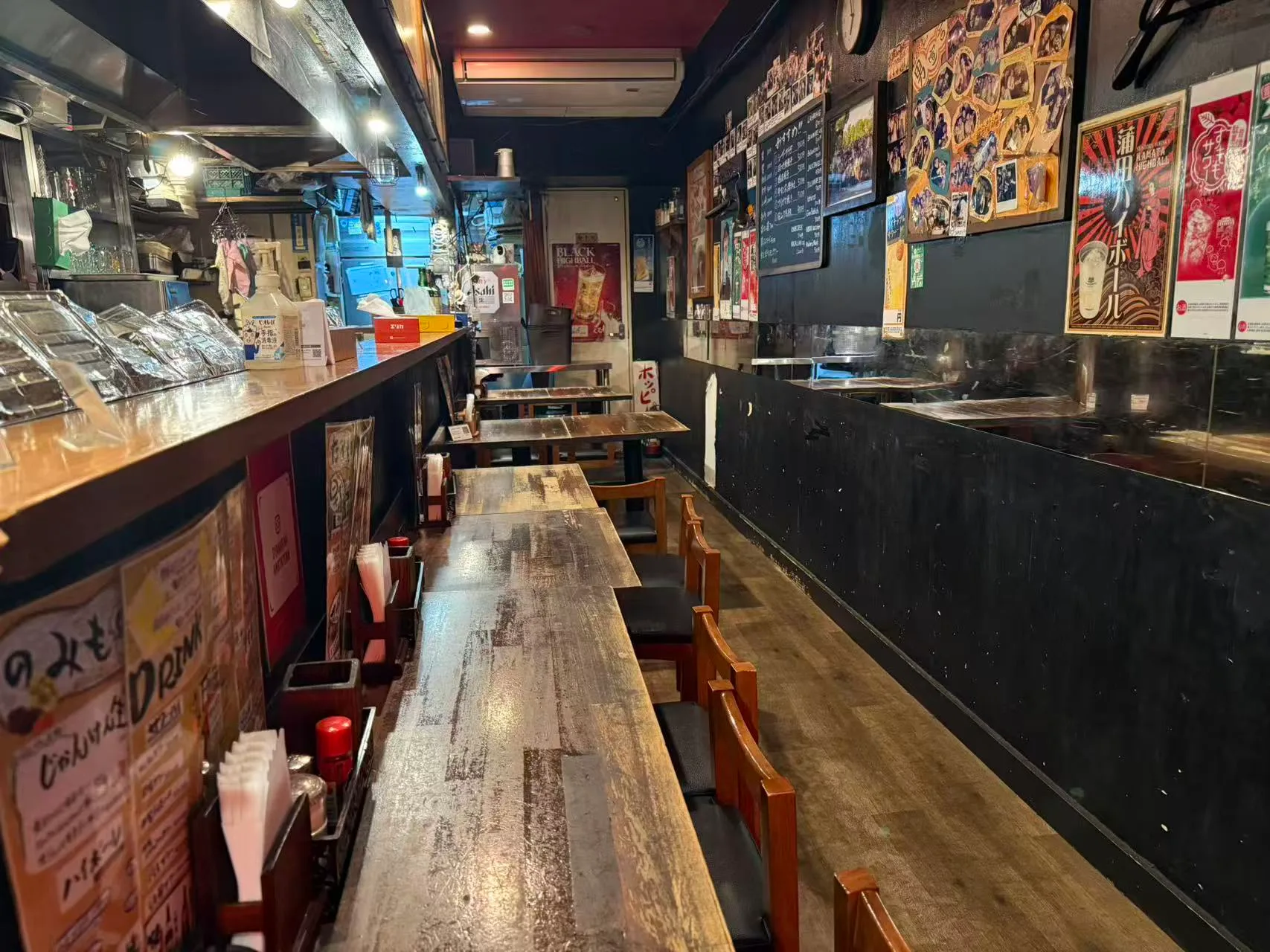 木のカウンター席と奥のテーブル席に照明が灯る夜の店内
